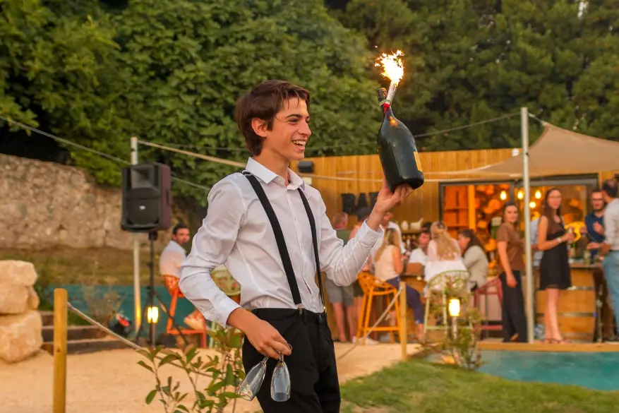 Un serveur emmenant une bouteille de champagne avec bougie